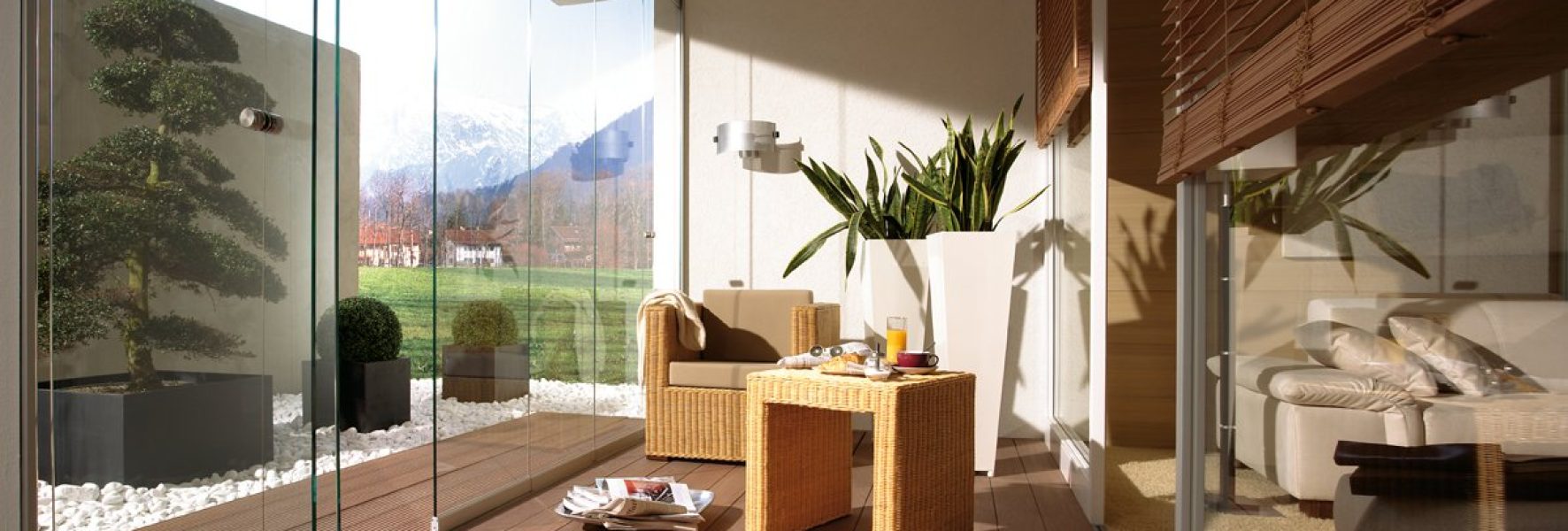 Die Holzterrasse ist mit Glas-Schiebewänden ausgestattet, 2 Glaselemente sind zur Seite geschoben.